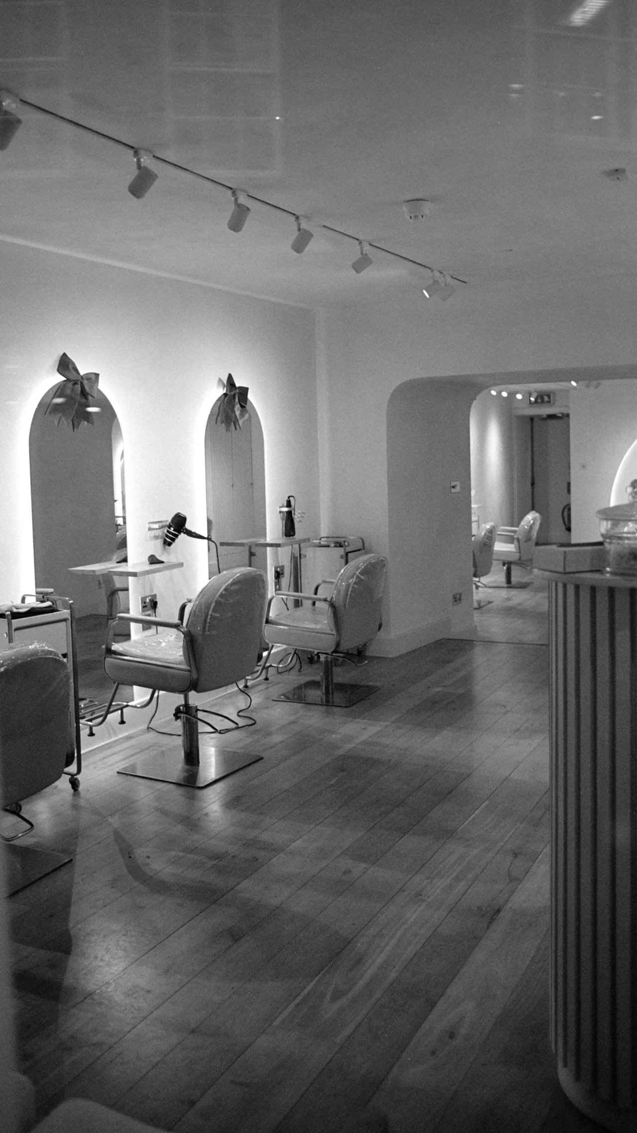 Salone raccolto con poltrone e specchi ad arco, in bianco e nero